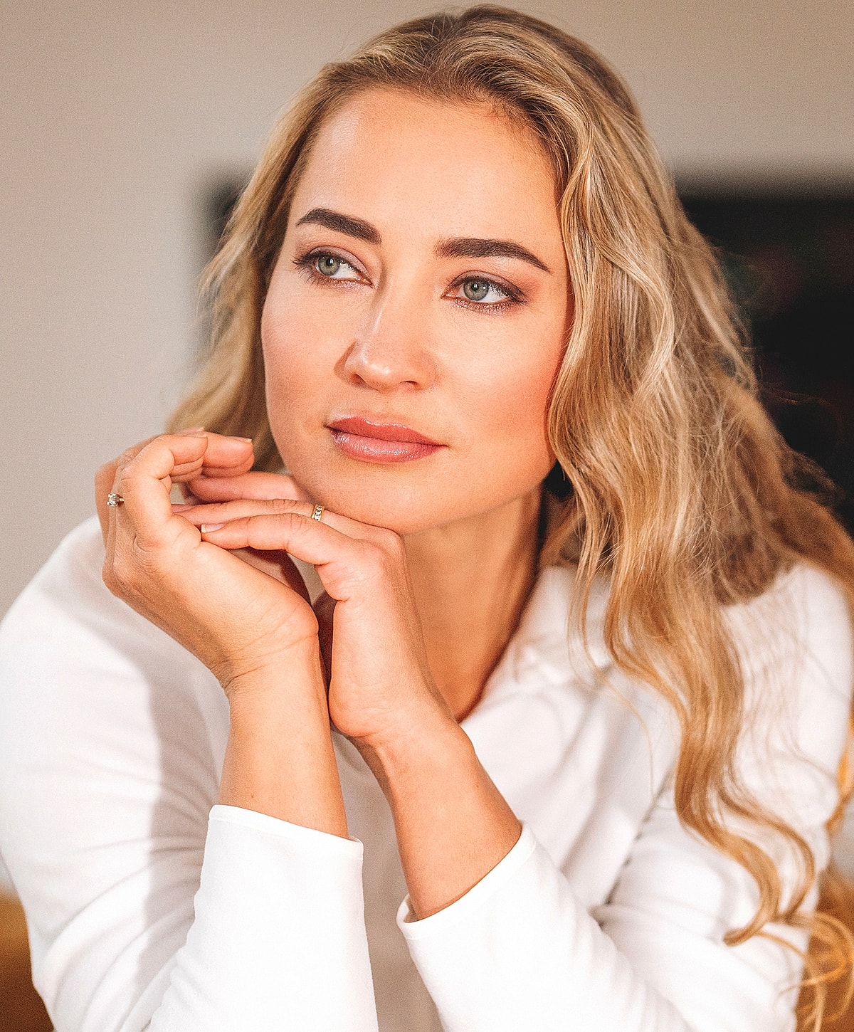 Woman with blonde hair resting her chin thoughtfully.