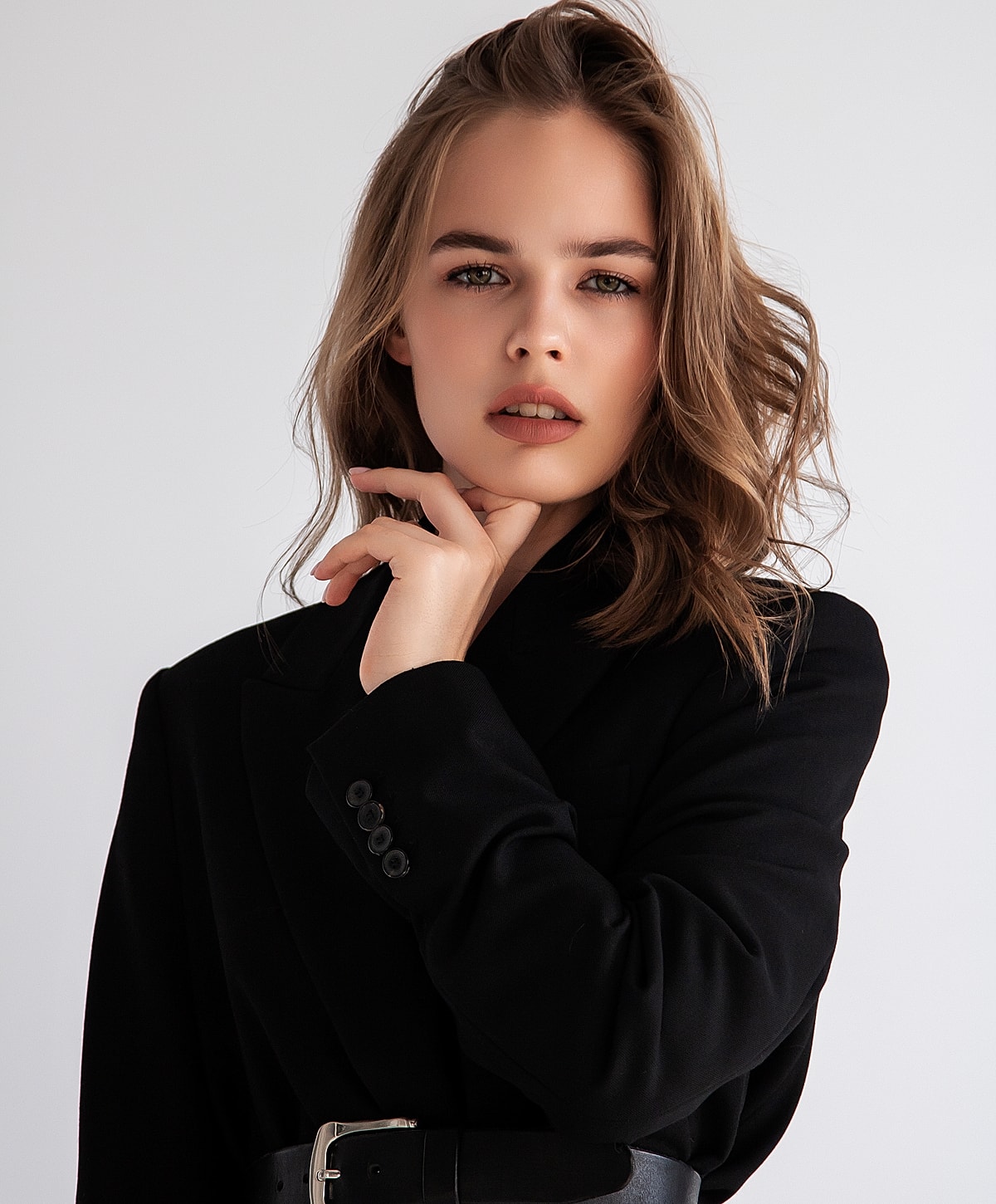 Woman in black blazer with thoughtful expression.