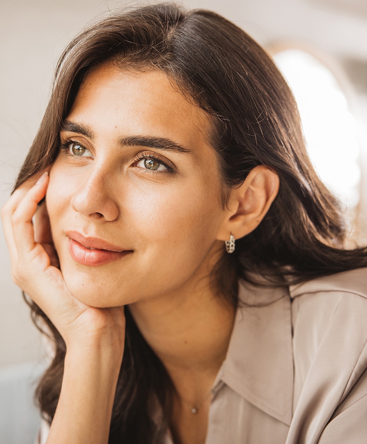 Thoughtful young woman resting her chin on hand.