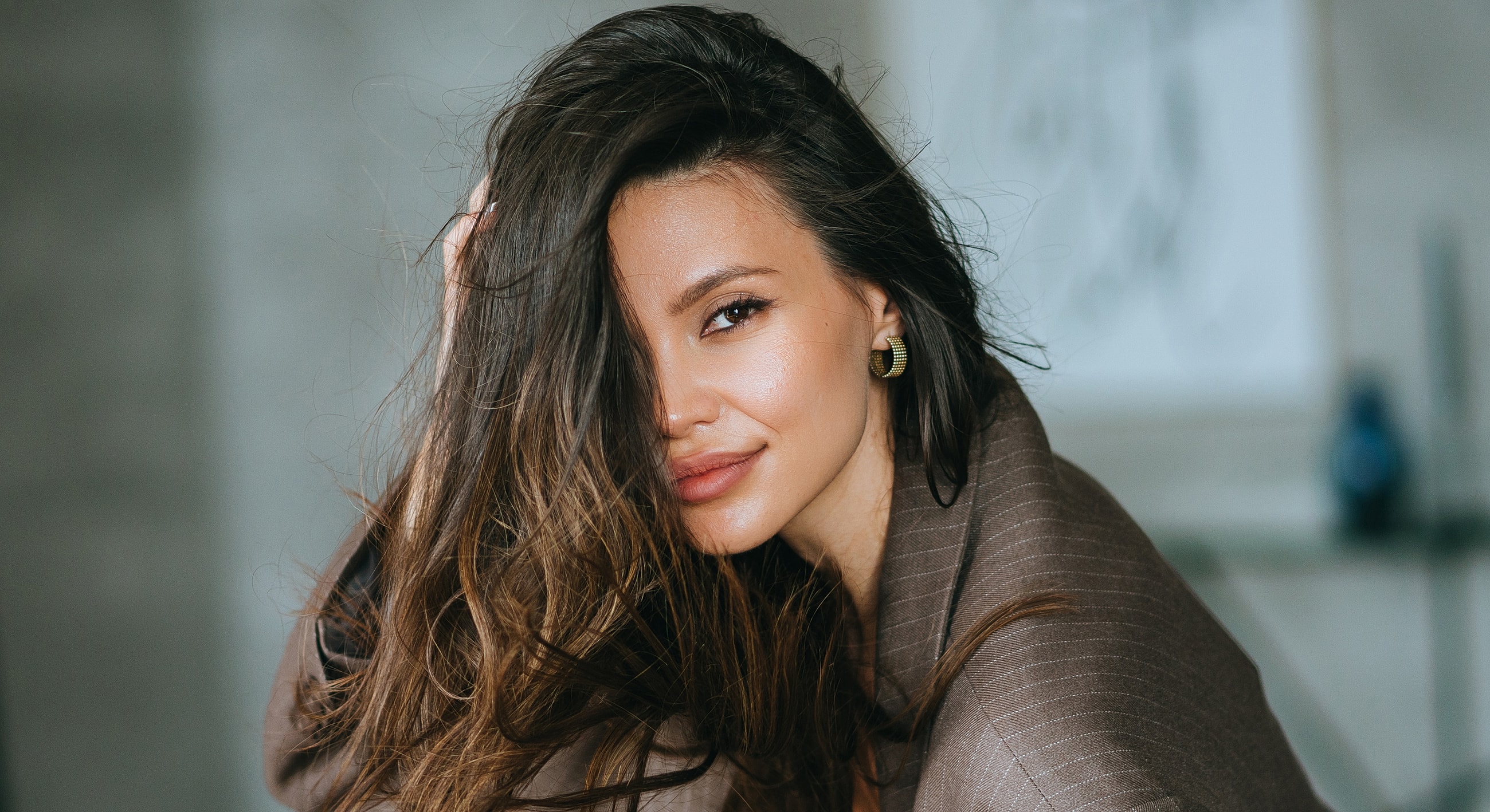 Woman with long hair smiling playfully indoors.