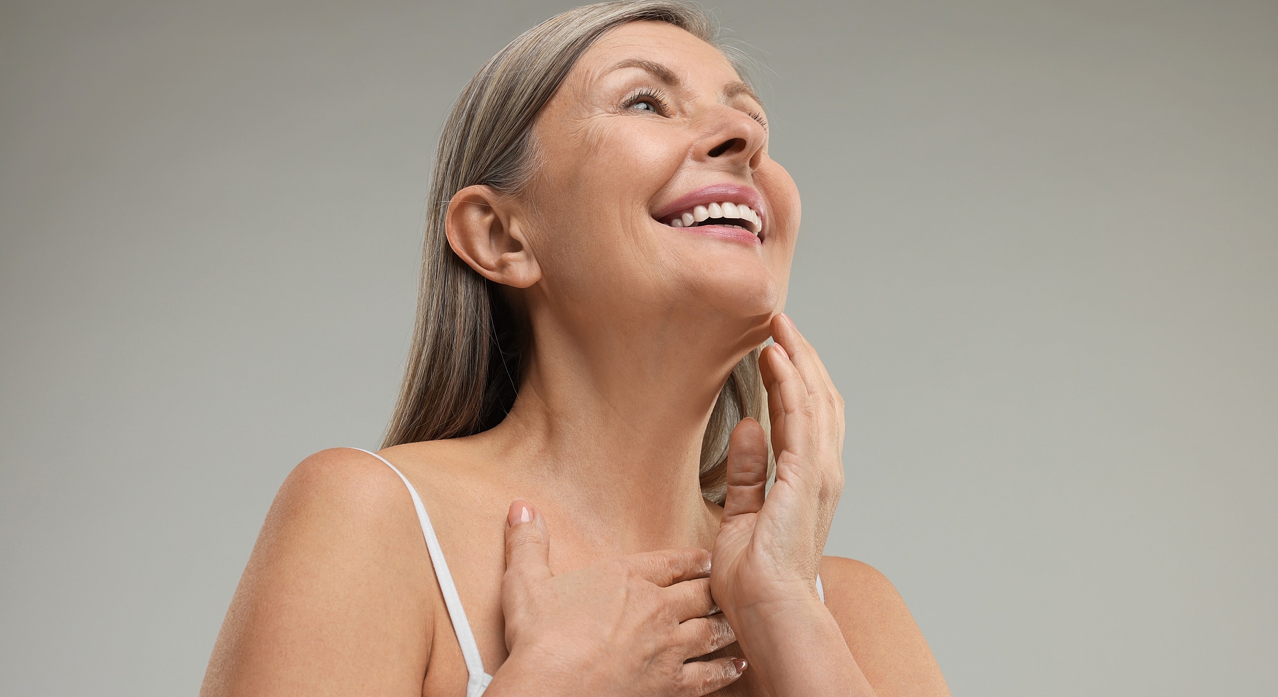 Smiling older woman touching her face.